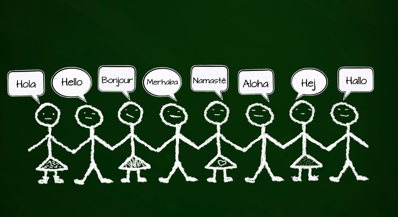 Eight stick figures drawn in chalk are holding hands. The background is a dark green and the stick figures are saying 'hello' in various languages.