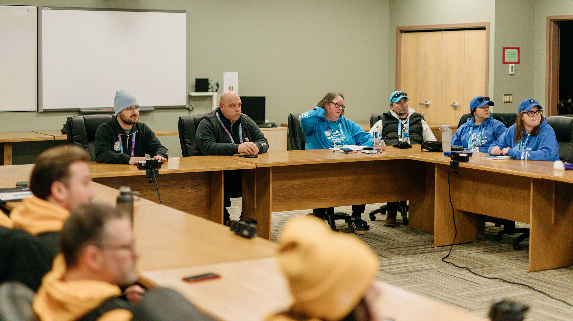 Numerous volunteers are seated at wooden tables to plan Saskatchewan Winter Games.