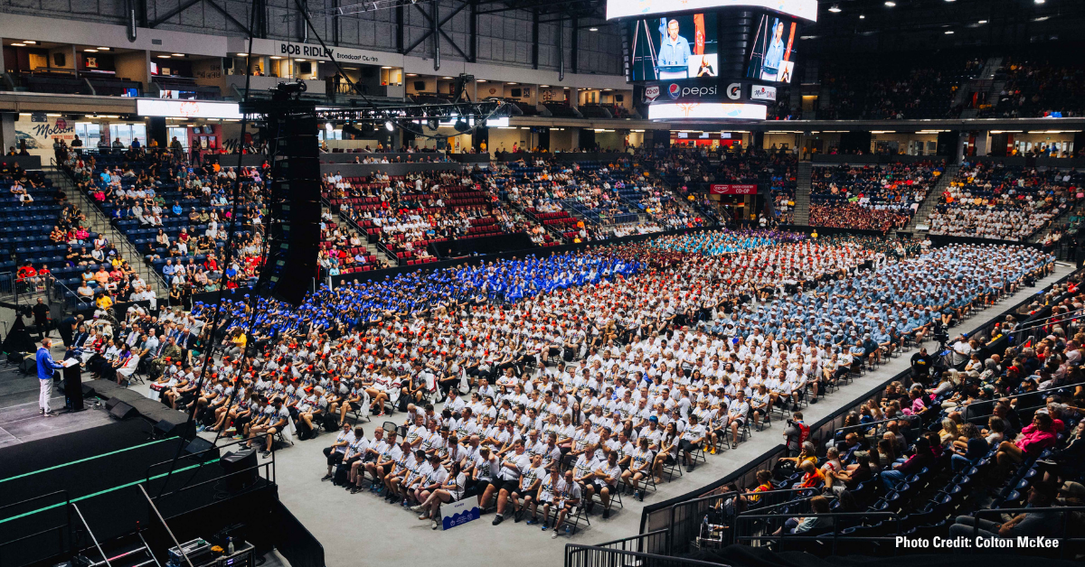 A large indoor arena is filled with various provincial teams, seated in sections and wearing coordinated outfits.
